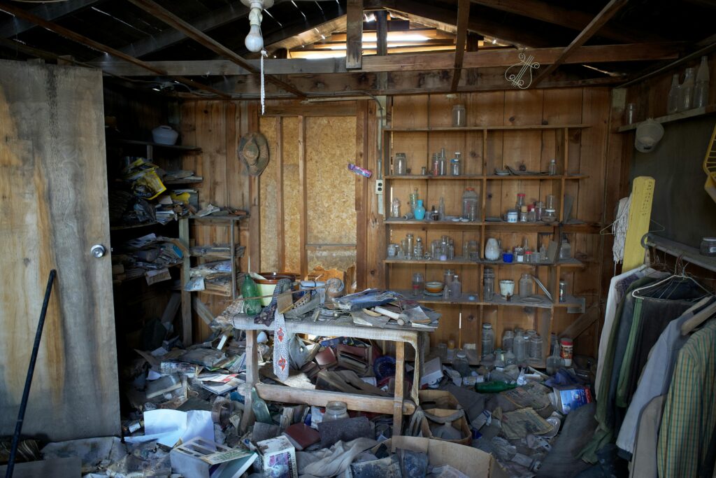 Interior view of an abandoned room filled with dusty and disorganized items, typical of urban decay.