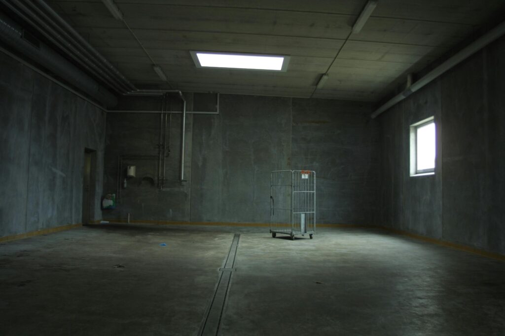 Dark empty industrial room with an abandoned cart, highlighting isolation and emptiness.